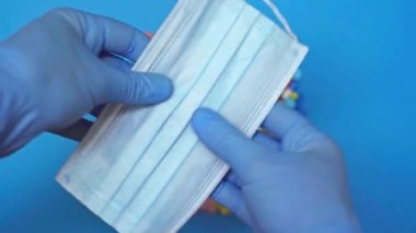 Mavi arka planda hapların yanında tıbbi maske tutan doktorların en iyi görüntüsü.