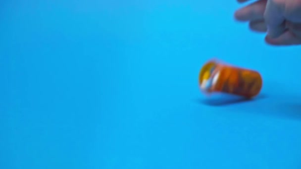 Mouvement lent de l'homme jetant pot avec des pilules colorées sur fond bleu 