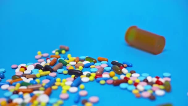 Mouvement lent du pot roulant sur des pilules colorées sur fond bleu 