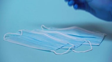 Doktorun mavi maskenin yanında Coronavirus örneği tutarken çekilmiş görüntüsü.