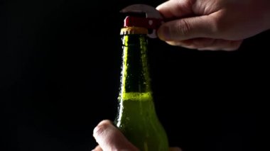 Siyah üzerine izole edilmiş hafif bira şişesi açan adamın görüntüsü.