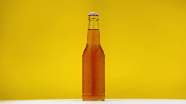 Botella Cerveza Ligera Girando Sobre Superficie Blanca Aislada Amarillo — Vídeos de Stock