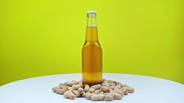 Botella Cerveza Cerca Pistachos Girando Sobre Una Superficie Blanca Aislada — Vídeos de Stock