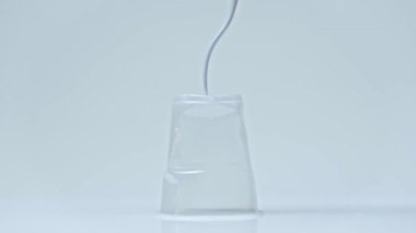 Kırmızıda çatalla plastik bardağa basan adamın görüntüsü.