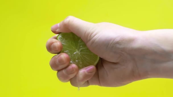 緑色でゆっくりとした動きで単離されたライムジュースを絞る男性の手 — ストック動画