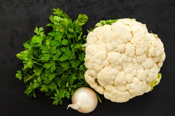White cauliflower, fresh green parsley and white onion on black background. Healthy eating concept. Top view. Closeup — Stock Photo, Image