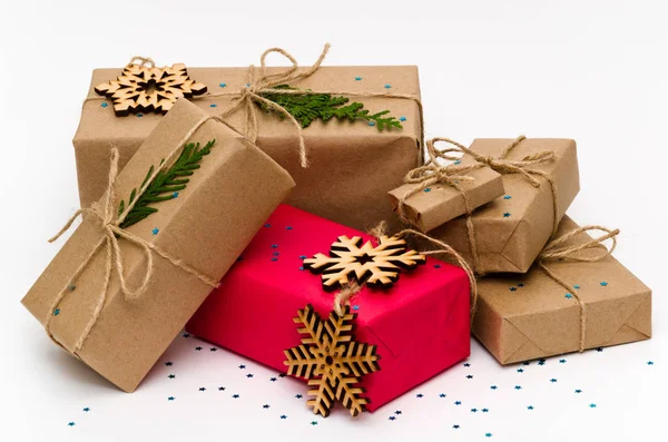 堆积如山的礼品盒，用手工褐色纸包着，粉红的礼品盒，白色的背景装饰着闪亮的蓝星和木制雪花。 圣诞节和新年假期的概念。 包扎 — 图库照片