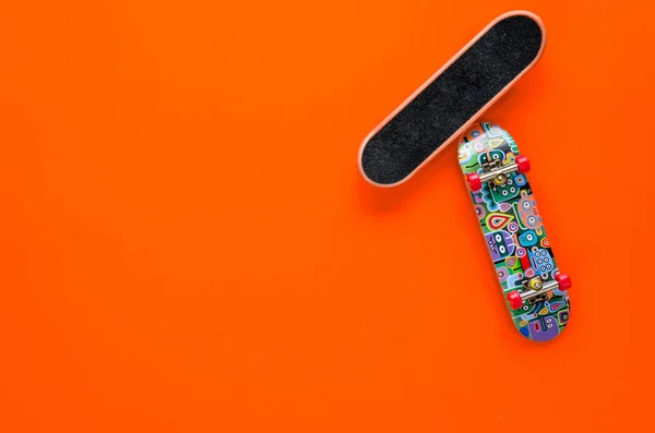 주황색 배경에 빨간 바퀴달린 작은 스케이트보드 장난감 두 개. 십 대 여가 개념. 납작 한 바닥. 복사 공간 — 스톡 사진