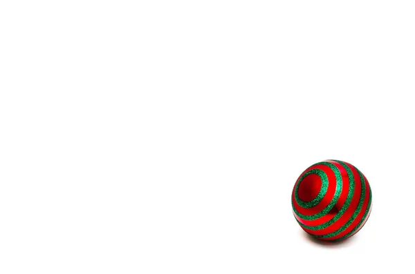 Single red christmas ball with green circular stripes on a white background. Minimal Christmas holiday composition. Layout, copy space — Stock Photo, Image