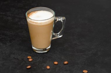 Siyah arka planda sütlü bir bardak kahve. Şeffaf bardakta sıcak latte veya cappuccino. Sabah içeceği. - Yakın çekim. Boşluğu kopyala