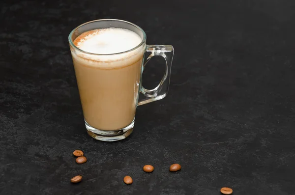 Un vaso de café con leche sobre fondo negro. Latte caliente o capuchino en taza transparente. Bebida de la mañana. Primer plano. Copiar espacio — Foto de Stock