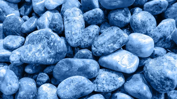 Nasse Kieselsteine in klassisch blauer Farbe. abstrakte natürliche trendige Hintergrund. Zentral und ruhig. Nahaufnahme. Selektiver Fokus — Stockfoto
