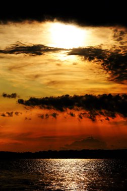 Nehir üzerinde kırmızı dramatik gökyüzünde gün batımı. Nehir yüzeyinde yansıma