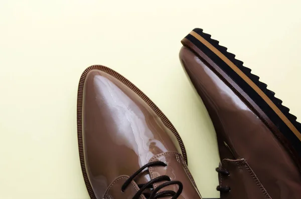 Detailní záběr stylově hnědé samičí kožené obuvi na pastelově světle žlutém pozadí. Módní blog, časopis, koncept krásy. Minimální složení. Byt ležel, horní pohled — Stock fotografie