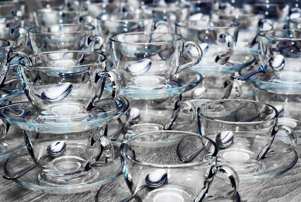 Copos transparentes de vidro limpo vazio com pires, colheres de chá na mesa de madeira cinza. Catering, chá partido preparação conceito — Fotografia de Stock