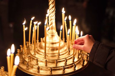 Karanlıkta Hıristiyan kilisesinde mum yakan dua eden kadının eli. Dini bir kavram. Yakın plan.