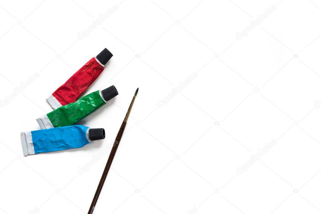 Tubes with red, green, blue acrylic paints and paintbrush isolated on white background. RGB colors. Creativity and hobby concept. Copy space