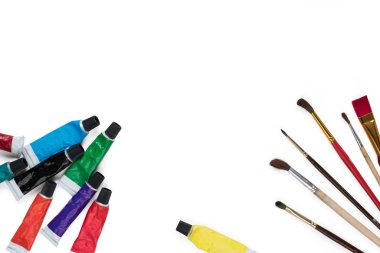 Beyaz arka planda izole edilmiş çok renkli akrilik boya ve boya fırçaları olan tüpler. Yaratıcılık ve hobi konsepti. Boşluğu kopyala