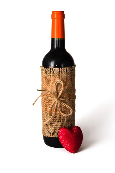 Flasche Rotwein in Kleckse eingewickelt, mit Bindfäden und rotem Herz auf weißem Hintergrund. Valentinstag. Nahaufnahme. Kopierraum — Stockfoto