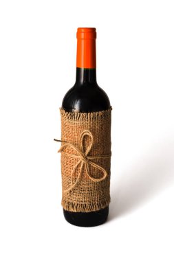 Beyaz arka planda sicimle bağlanmış çuvala sarılmış bir şişe kırmızı şarap. Tatil konsepti. Diy hediye paketleme fikri. Yakın plan. Boşluğu kopyala