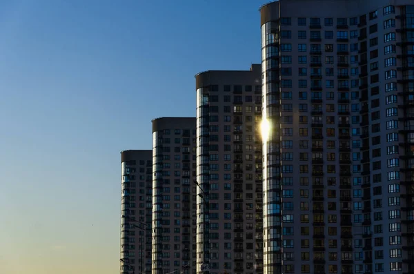 Row of modern high-rise buildings against clear blue sky in perspective. Urban background. Urban sprawl concept. Outdoors. — Stock Photo, Image