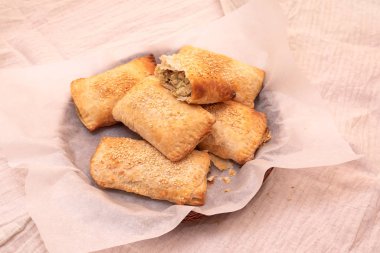 Beyaz parşömen üzerine susam tohumu serpiştirilmiş mantar ve yumurtalarla doldurulmuş ev yapımı poğaçalı börekler. Lezzetli aperatif.