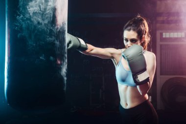 Kum torbasında boks antrenmanı yapan genç bir kadın - spor, kendini savunma, boks ve eğitim kavramları - çapraz boks
