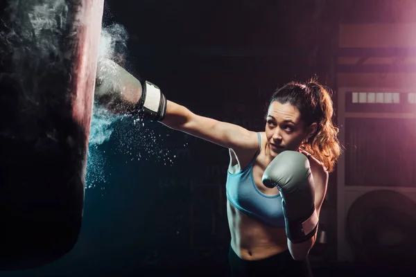 Entrenamiento de la mujer joven boxeo en el saco de boxeo - deporte, defensa personal, boxeo y conceptos de entrenamiento - swing boxeo — Foto de Stock