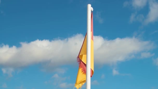 Bandeira Vermelho Amarelo Pendurado Pólo Contra Céu Azul Com Nuvens — Vídeo de Stock