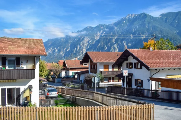 Köydeki evlerin çatıları Alplerdeki dağların arka planına karşı. — Stok fotoğraf
