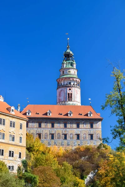 Oude hoge toren met zuilen boven het gebouw en bomen met gele bladeren in Europa — Stockfoto