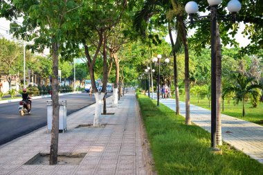 NHA TRANG, VIETNAM - APRIL 18, 2019: Tropical trees and footpath along road in Vietnam in the morning