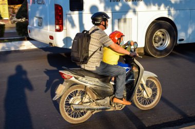NHA TRANG, VIETNAM - APRIL 18, 2019: Father and child in a helmet on old motorcycle on a road in Asia