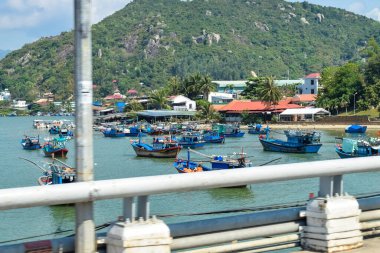 NHA TRANG, VIETNAM - APRIL 18, 2019: Boats with cargo on the river and green island with tropical trees.