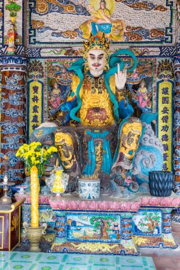 Dalat, Vietnam - 15 Nisan 2019: Vietnam 'da bir duvarda çiçekler ve fresk olan bir tapınakta Budist heykeli