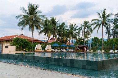 NHA TRANG, VİETNAM - 19 Nisan 2019: Palmiye ağaçları ve fenerlerin altında havuz ve güneşlik