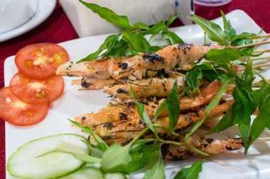 Yeşil çimenli kızarmış karides ve tabakta domates.