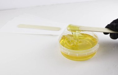 Şeker ezmesi, tahta bir spatulayla kavanozda şekerleme yapmak için siyah bir tıbbi eldivenin içindeki bir elle tutulur. Saç kesimi, tüy dökümü..