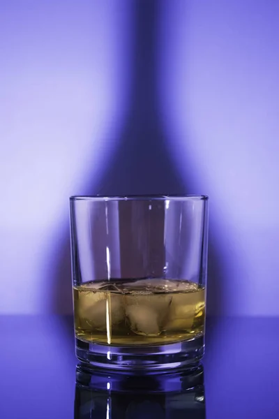 青い光の中で氷とガラスウイスキーグラス — ストック写真