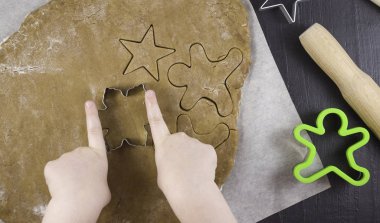 Çocukların elleri hamurdan zencefilli ekmek kalıpları kesiyor. Aile tatilleri, tatlı pastalar, çocuklarla yemek pişirme.