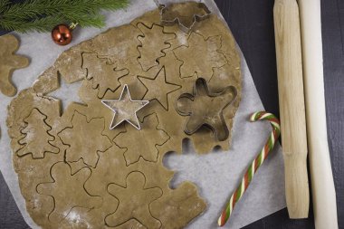 Zencefilli kurabiye evleri, zencefilli çörekler, yıldızlar ve Noel ağaçları için para. Tatil yemeği. Noel ağacının yeşil dalları ve yakınlarda bir şeker kamışı.