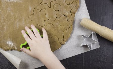 Çocukların elleri hamurdan zencefilli ekmek kalıpları kesiyor. Aile tatilleri, tatlı pastalar, çocuklarla yemek pişirme.