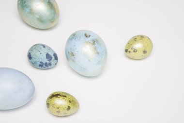 Beyaz arka planda altın elementli mavi Paskalya yumurtaları. Minimalizm. Metin için boş alan. Mutlu Paskalyalar!