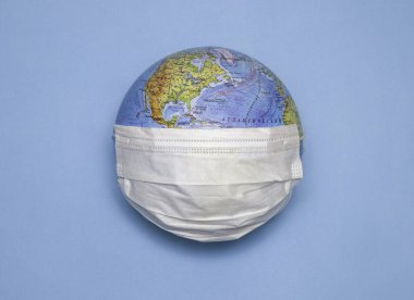 Dünyadaki tek kullanımlık tıbbi maske, Dünya 'nın modeli. Salgın konsepti. Covid-19, koronavirüs. Hastalığın dünya salgını. Kapsamlı Tehlikeli Virüs.
