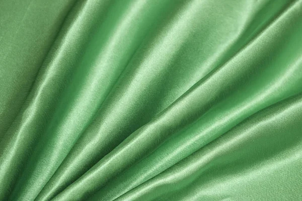 Smooth elegant green silk or satin luxury cloth texture can be used as an abstract background. Crumpled fabric.