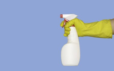 Lastik eldivenli bir el, temizleyici ya da dezenfektan içeren bir sprey silah tutar. İzole edilmiş, mavi arkaplan, metin için boş alan.