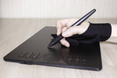 Özel eldivenli bir kadının eli grafik tabletine çizim yapar. Yan görünüm, grafik çizim araçları.