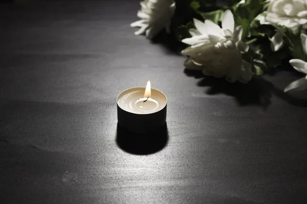 葬儀のシンボル 黒い背景に燃えるろうそく 背景に白い花の花束 サイドビュー — ストック写真