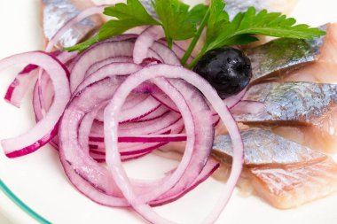 Dilimlenmiş kırmızı soğan ile lezzetli tuzlanmış ringa balığı.