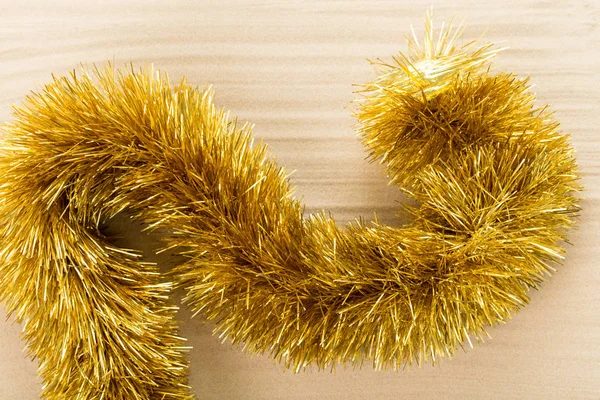 Golden christmas tinsel on waved sand. — Stock Photo, Image